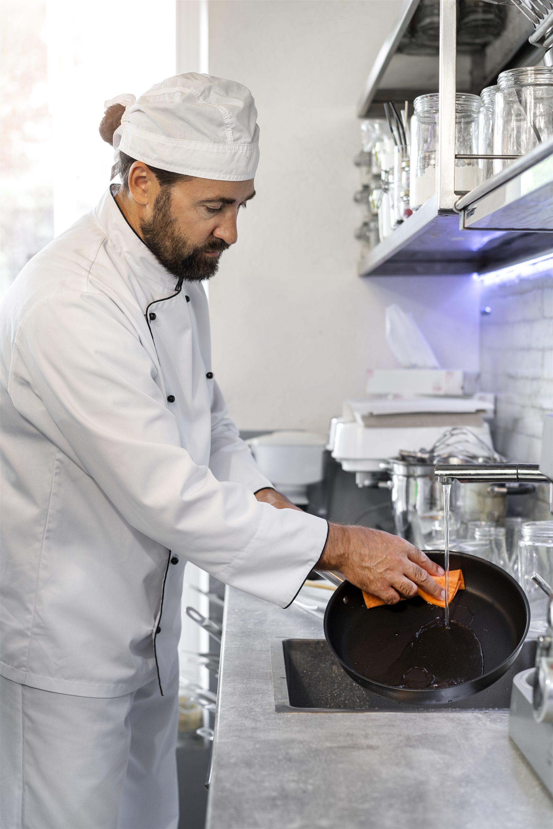Chef cleaning cookware in a professional kitchen
